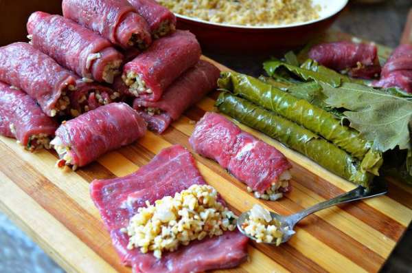 На каждый кусочек мяса укладываем подготовленную начинку, плотно сворачиваем. Большие рулетики можно разделить пополам. Затем каждый мясной рулетик заворачиваем в виноградный лист.
