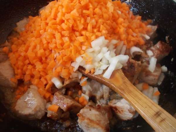 Обжариваем мясо на раскаленном масле до золотистой корочки, добавляем лук и морковь.