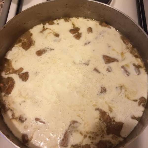 Залить мясо сметаной и, помешивая, довести до кипения. Уменьшить огонь и тушить 10 — 15 минут.