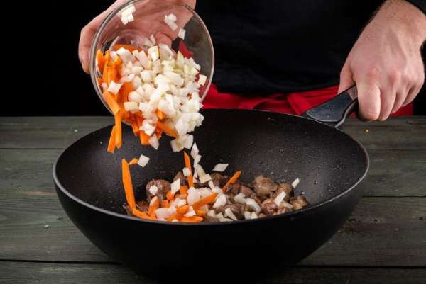 Морковь и лук очистить и нарезать, выложить в жаровню к мясу, обжарить. 