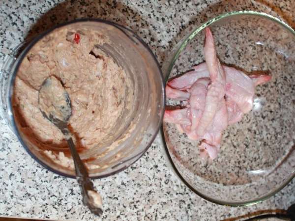 Крылышки промыть, аккуратно, надрезая ножом, отделить кожу от мяса и костей в двух фалангах, самую маленькую фалангу не трогать — должен получиться чулок из кожицы. 
Сделать фарш: отделить мясо крылышек от костей, поместить в блендер. Добавить нарезанный помидор, зубчики чеснока, соль, соевый соус, сырое яйцо, перец, майонез Провансаль ТМ «Слобода», орехи. Все хорошо взбить. 