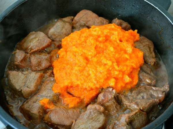 Выложить к мясу измельченные овощи, как следует перемешать, уменьшить огонь и тушить пока мясо не станет мягким, а соус не загустеет. 