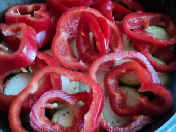 Перец почистить от семян, порезать кольцами и положить на кабачки.