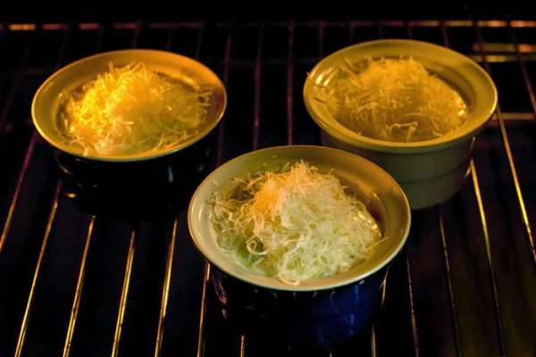 Выложить морепродукты с соусом в формочки для жюльена, посыпать сыром и запекать в разогретой до 180°C духовке 5 минут.

