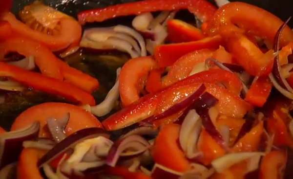 В сковороде, где жарилось куриное мясо, разогреть оставшееся оливковое масло, выложить лук, сладкий перец и помидоры, посолить и томить 5–7 минут до мягкости.