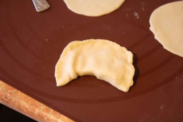 Смажем края мокрой кисточкой и защипнем хорошенько. Сформируем наш пирожок в виде полумесяца.