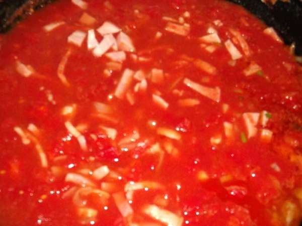 На оливковом масле немного обжариваем нарезанный лук и чеснок и нарезанную курицу, добавляем две банки консервированных нарезанных томатов (можно томатный соус).