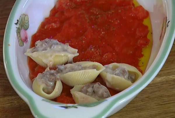 Отваренные ракушки наполнить фаршем с соусом и выложить в форму с томатами.