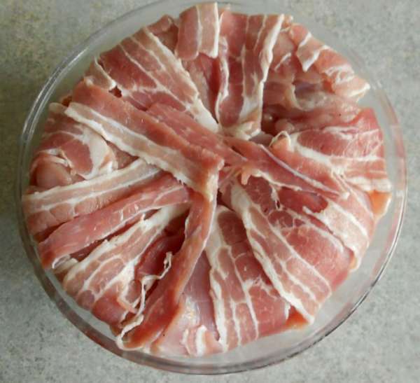 Закройте мясо свисающими полосками бекона.

Поставьте форму в разогретую до 180*С духовку на 30-40 минут.
За это время 'бомба' приобретёт устойчивую форму, а из мяса начнёт выделяться сок.