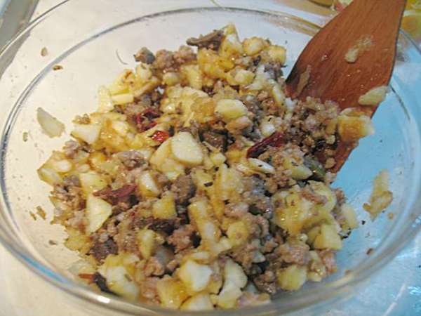 Вынутую мякоть яблок нарезать на кусочки и сбрызнуть лимонным соком. Порезанную мякоть добавить к фаршу. Перемешать, посолить, поперчить начинку для яблок. 