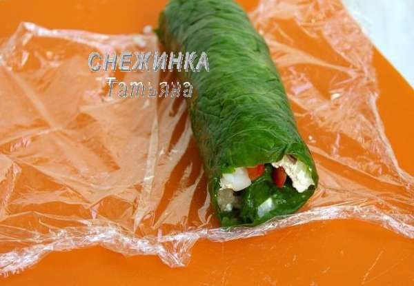 Помогая себе пищевой плёнкой, сворачиваем аккуратно достаточно плотный рулет. Заворачиваем его в плёнку и отправляем на минут 30 в холодильник.

