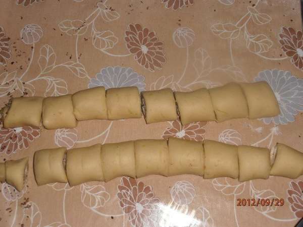 Раскатать тесто, смазать начинкой (можно посыпать тертым шоколадом) и закрутить рулетиком с обеих сторон и нарезать на кусочки см по 4-5.