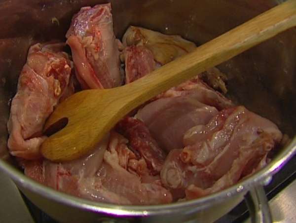 Тушку кролика порезать кусочками, выложить в кастрюлю к овощам и обжаривать до золотистого цвета.