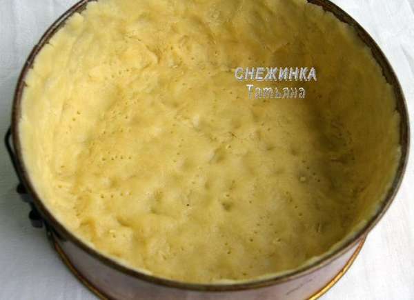 Вынимаем тесто. Раскатываем его и выкладываем в форму. Я немного раскатала, чуть больше по диаметру величины дна формы, а дальше руками распределяла тесто. Делаем высокие бортики – 6 см (на всю высоту формы). Накалываем в нескольких местах тесто вилкой (не прокалывая насквозь!).
