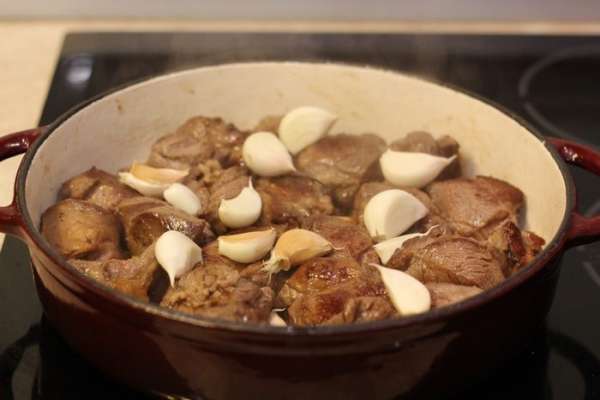 Посыпьте солью и сухими травами мясо. Добавьте чеснок в мясо, перемешайте и накройте крышкой. Сделайте очень маленький огонь.