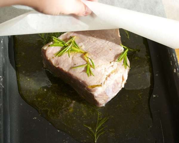 Затем выложить мясо на противень с высокими бортиками... Вылить на мясо часть маринада. И закрыть большим листом пекарской бумаги...