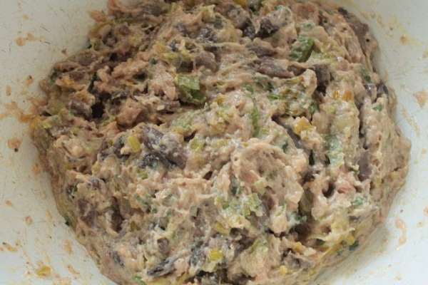 Приготовить фарш из срезанных кусочков мяса. С десяти ножек у меня получилось  200 граммов. Шампиньоны нарезать мелко, лук-порей полукольцами. В сковороде с растительным маслом обжарить шампиньоны до испарения жидкости, добавить лук-порей, перемешать и прогреть 2 минуты, остудить. Добавить к мясному фаршу. Добавить остальной сыр, желток одного яйца,столовую ложку белых панировочных сухарей, зелень петрушки и соль, перец по вкусу, хорошо перемешать.