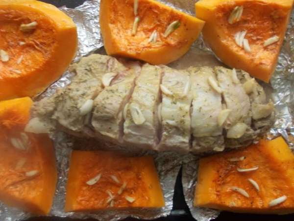Через час запекания, достать мясо и развернуть фольгу. Выложить рядом с мясом тыкву. По сыпать мелко порезанным чесноком и поставить запекаться еще на пол часа.