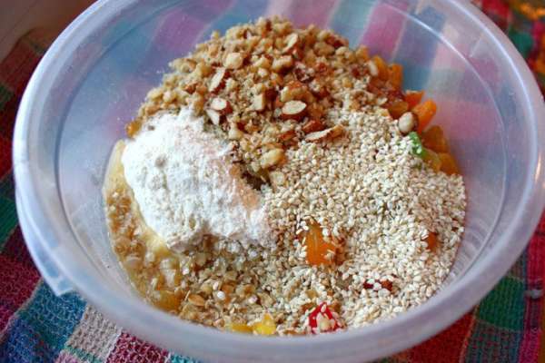 Затем в миску с овсянкой добавить орехи, кунжутные семечки, цукаты, курагу (заранее нарезанную полосками), изум, масло, муку пшеничную и овсяную.
Все тщательно перемешать.