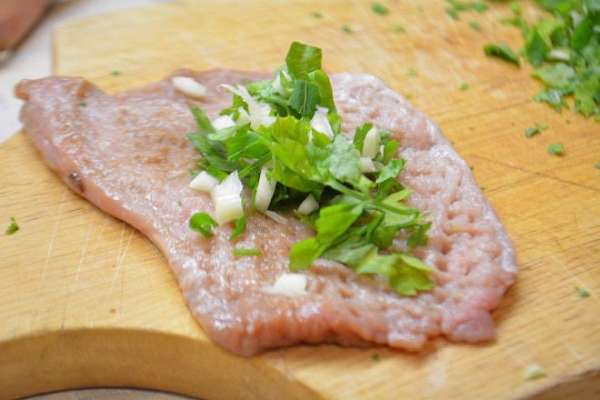 На кусочек мяса кладем немного зелени с чесноком.