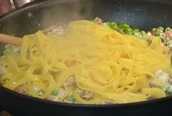 Шумовкой вынуть из кастрюли готовые макароны и переложить в сковороду с грибами и горошком, влить 1 половник воды, в которой они варились и, непрерывно перемешивая, прогревать еще пару минут, затем снять с огня.