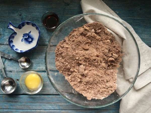 Добавьте сливочное масло, порезанное на кубики, щепотку соли и перемешайте до получения крошки. Введите желток, ванильный экстракт и 2 ст. л. холодной воды. 