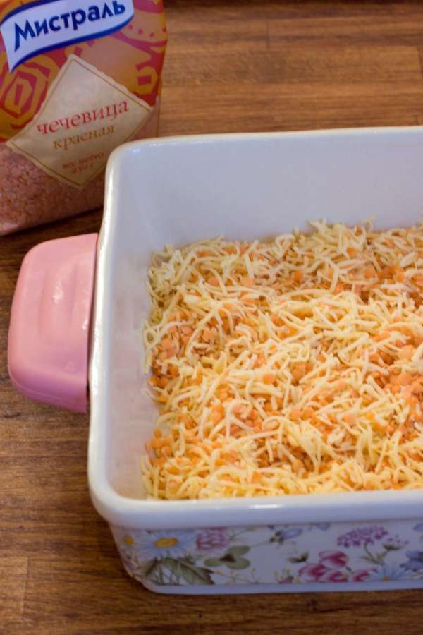 Форму для запекания смазать сл.маслом и первым слоем выложить сырую красную чечевицу, смешанную с половиной от всего количества натертого сыра.