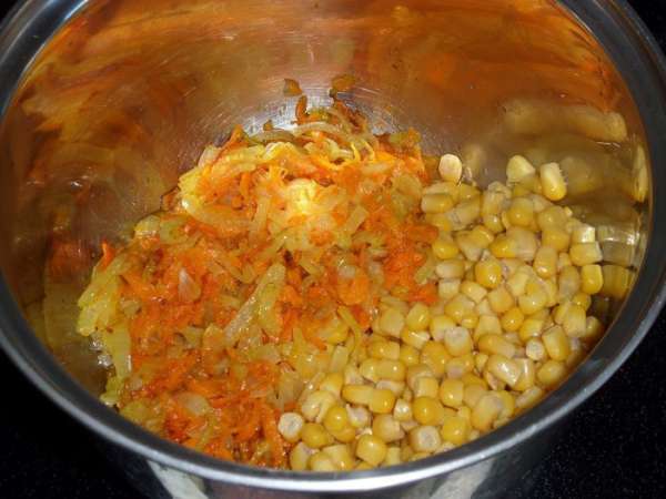 В кастрюлю выкладываем обжаренные овощи и консервированную кукурузу.