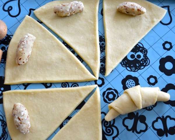 Из каждого кусочка марципановой начинки скатайте маленькую колбаску и выложите на тесто с более широкого конца. Сверните рогалик, наподобие круассана. Таким же образом приготовьте все остальные рогалики. Из каждого кусочка марципановой начинки скатайте маленькую колбаску и выложите на тесто с более широкого конца. Сверните рогалик, наподобие круассана. Таким же образом приготовьте все остальные рогалики.