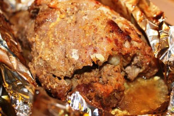 Запекать при температуре 200 градусов 30 минут. Затем убавить ее до 180 градусов и запекать еще 1 час. После этого надрезать сверху фольгу, раскрыть ее немного, полить мясо образовавшимся соком и запекать в таком виде еще минут 15, чтобы мясо подрумянилось. В общей сложности потребуется около двух часов.