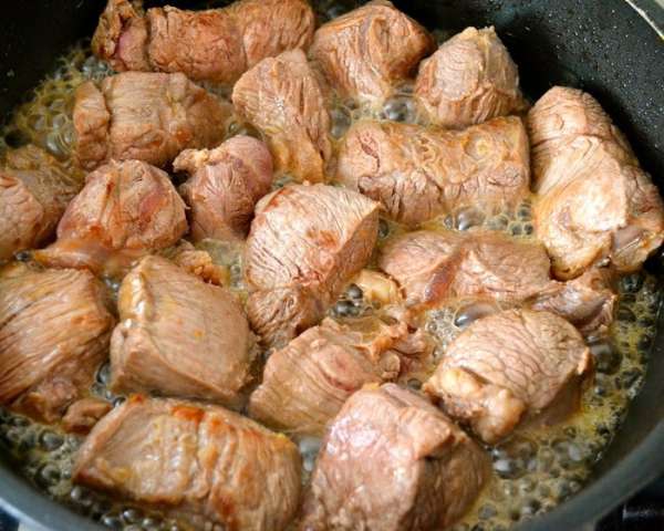 На сковороду, где обжаривались овощи, выложить кусочки мяса. При необходимости добавить немного масла. Обжарить мясо на сильном огне до образования золотистой корочки.  