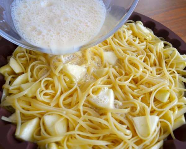 Форму смазать маслом, выложить в нее яблочно-макаронную смесь и залить молоком с яйцами. 