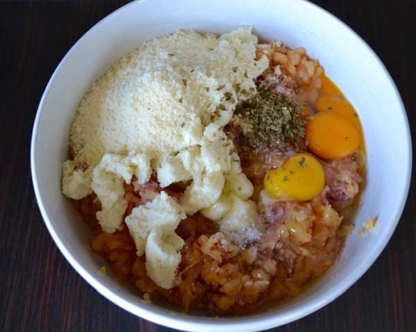 Приготовьте фарш из куриной грудки, добавьте свиную колбаску, 2 яйца, тертый сыр пармезан, отжатый от молока хлеб, измельченную зелень петрушки и щепотку соли. 