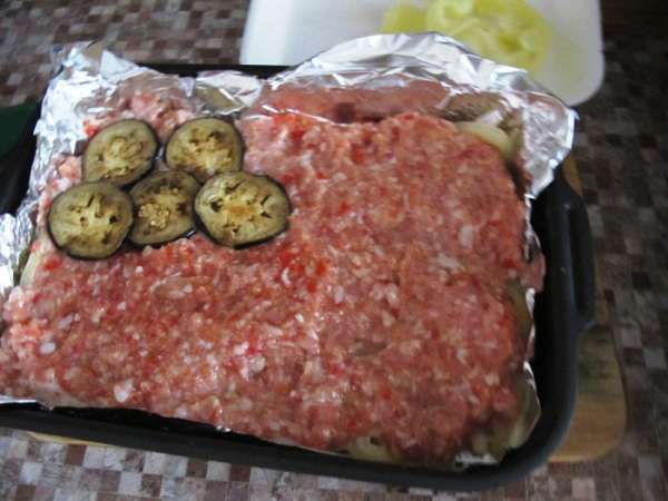 Затем выкладываем слой мясного фарша. Баклажаны. Посыпаем базиликом. Поливаем соусом.