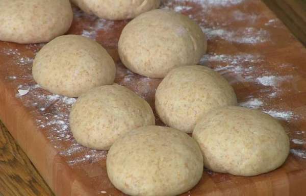 Отдохнувшее тесто выложить на посыпанную мукой рабочую поверхность, разделить на 8 частей, сформировать небольшие шарики, накрыть их сухим полотенцем и оставить для расстойки в теплом месте.