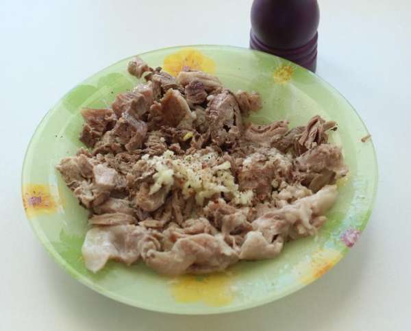 Мясо разобрать на кусочки, добавить молотый перец, выдавить чеснок.
