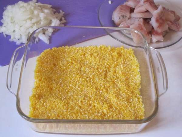 Выложить на дно формы для запекания кукурузную крупу. Посолить, поперчить.