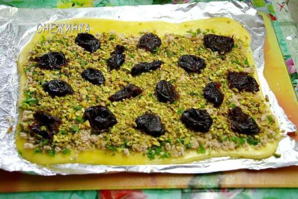 Снимаем пищевую плёнку. Распределяем курицу с зеленью, немного вдавливая в пласт. Верхний край оставляем немного свободным. Сверху – фисташки, затем – чернослив. Снимаем пищевую плёнку. Распределяем курицу с зеленью, немного вдавливая в пласт. Верхний край оставляем немного свободным. Сверху – фисташки, затем – чернослив.