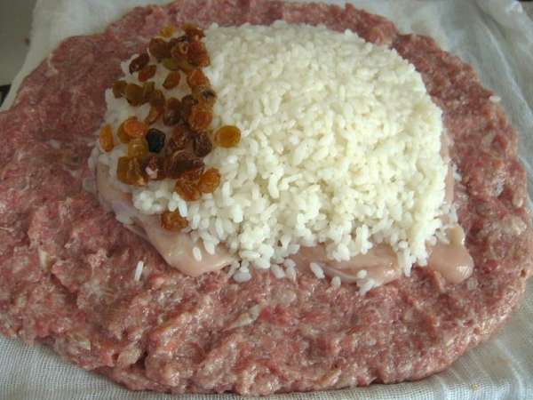 пропустить мясо баранины через мясорубку вместе с луком и чесноком.Посолить, поперчить,доб.хмели-сунели,вымесить фарш, если фарш очень крутой, добавить молока стакан.Готовый фарш выложить на приготовленную, смоченную в воде
ткань.На фарш выложить филе курицы,слегка отбитое.На филе отварной рис и изюм.