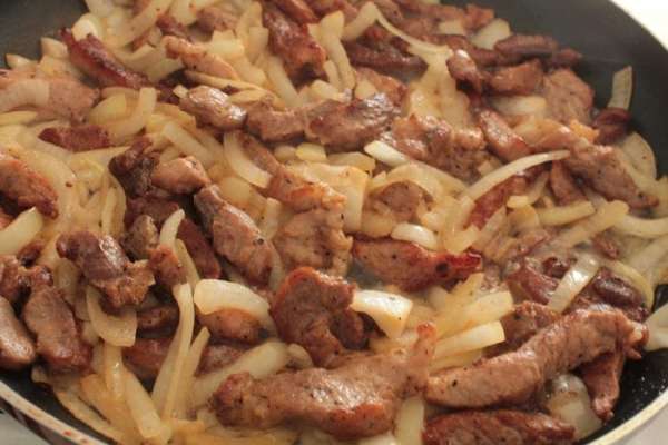 Нагреть на сильном огне сковороду с растительным маслом и обжарить мясо,помешивая,до румяной корочки.Затем убавить огонь до среднего,добавить лук и ,помешивая,обжарить до прозрачности лука.