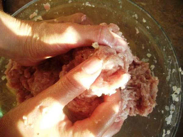 Затем пропускаем мясо, сало, лук, чеснок через мясорубку несколько раз.
Добавляем немного сухого базилика. 
В результате получаем однородный фарш. 
Хорошо перемешиваем фарш руками на протяжении 25 минут.