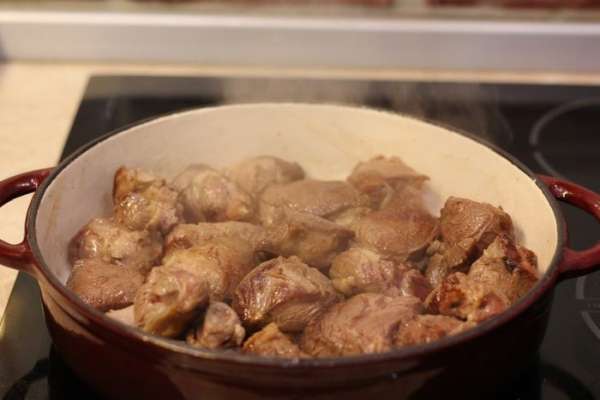 Если вы жарили мясо в несколько этапов - выложите все обжаренное мясо обратно в кастрюлю. Уменьшите огонь до маленького.
