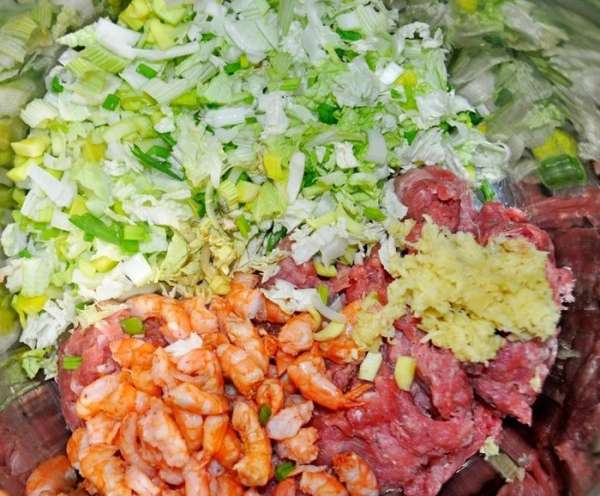 В свиной фарш добавить нарезанные на кусочки креветки (оставить 12 штук целыми и с хвостиками), нарезанные овощи, очищенный и натёртый на мелкой тёрке имбирный корень, соевый соус, креветочный бульон, перец по вкусу.