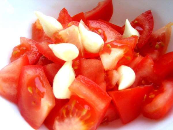 Чистые помидоры нарезать на кусочки, добавить очищенный чеснок.