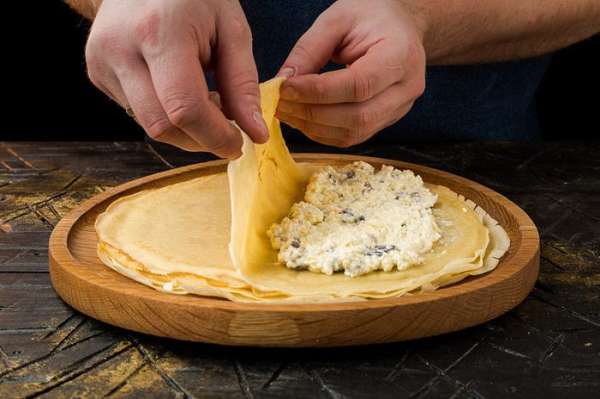 Разогреть блинную сковороду и, смазывая ее при помощи кулинарной кисточки оливковым маслом, испечь блины. На одну половинку каждого блина выложить немного творожной начинки, накрыть другой половинкой и сложить пополам, чтобы получились треугольники. Разогреть блинную сковороду и, смазывая ее при помощи кулинарной кисточки оливковым маслом, испечь блины. На одну половинку каждого блина выложить немного творожной начинки, накрыть другой половинкой и сложить пополам, чтобы получились треугольники.