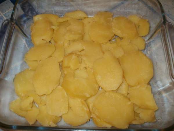 Отварной картофель нарезаем кружочками и выкладываем на дно формы, которую предварительно слегка смазываем растительным маслом.