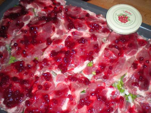 Сверху на мясо намазать брусничный соус.