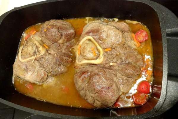 К мясу добавить пассерованные овощи, порезанный чеснок, и порезанные томаты. Посолить и поперчить. Закрыть крышкой и томить на медленном огне 2 часа, переворачивая каждые 20 минут. Если необходимо - то добавить воды.