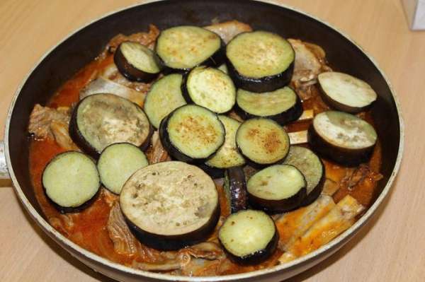 Когда мясо станет мягким, добавить баклажаны, предварительно обжаренные в другой сковороде. Аккуратно все перемешать, чтобы кружочки баклажан остались целыми. Потомить на медленном огне 5 минут. Выключить плиту, дать настояться 5 минут. На гарнир можно подать рис. 