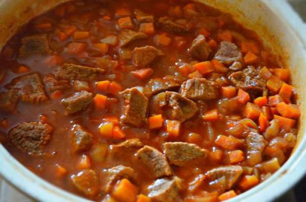 Мясо посолить, поперчить, добавить нарезанные лук и морковь, перемешать и тушить все вместе еще минут 20.